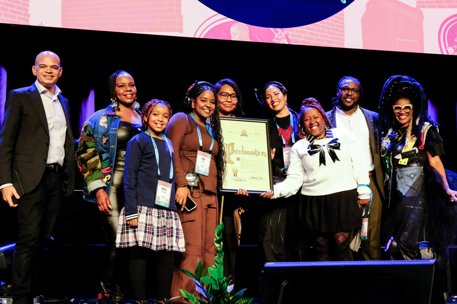 Facing Race team smiling while holding a framed proclamation on the main stage.