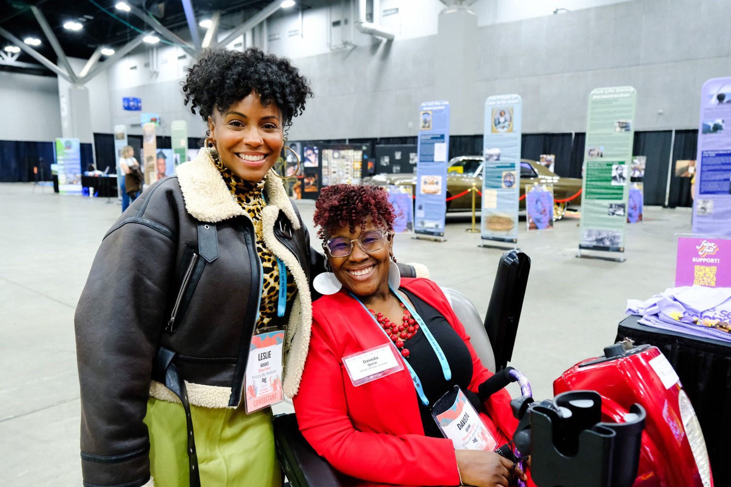 Two folks posing for a photo in front of exhibits.