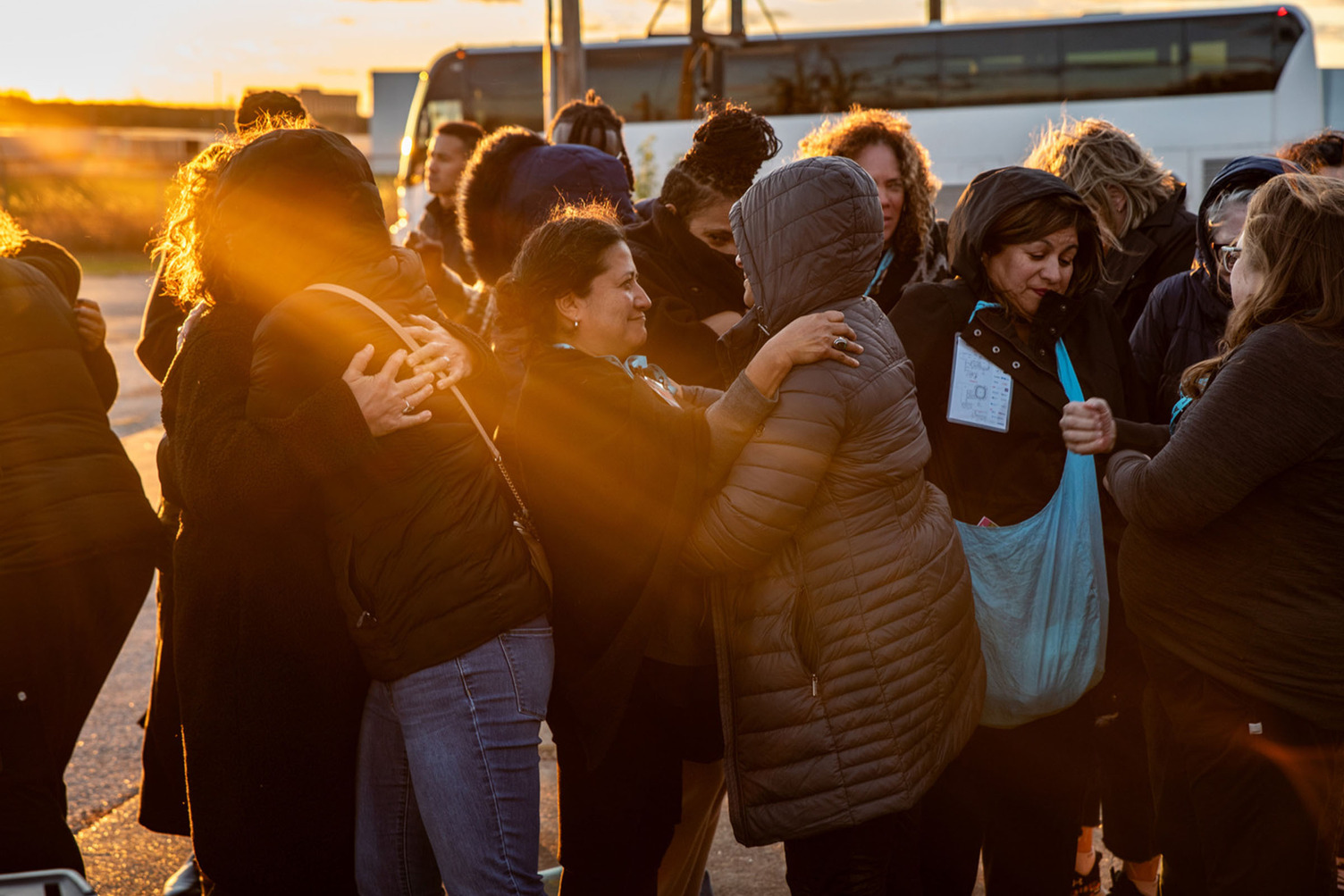 People greeting and hugging each other in the morning near a bus.