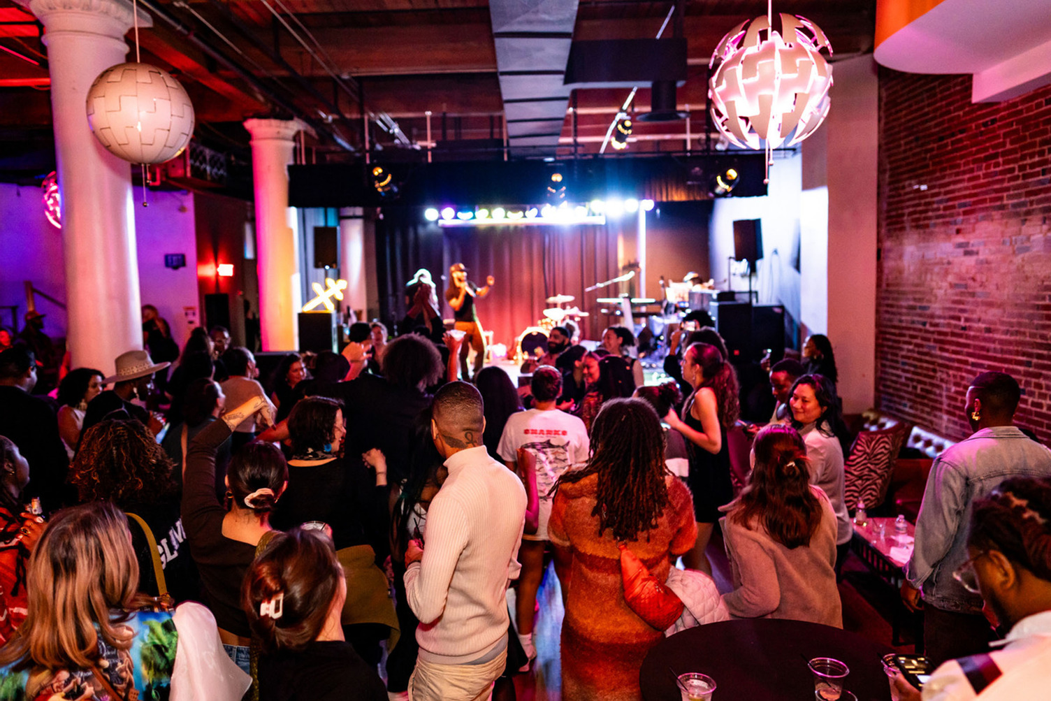 Crowd gathered in a decorated room in front of a stage with performers.