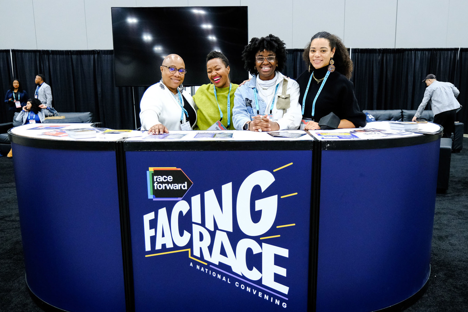 Folks hanging out and smiling to camera at the Facing Race information desk.