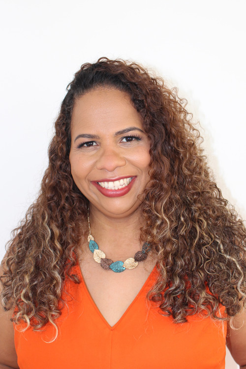 Person smiling with long curly hair.