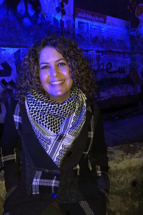 Person smiling and wearing a keffiyeh.