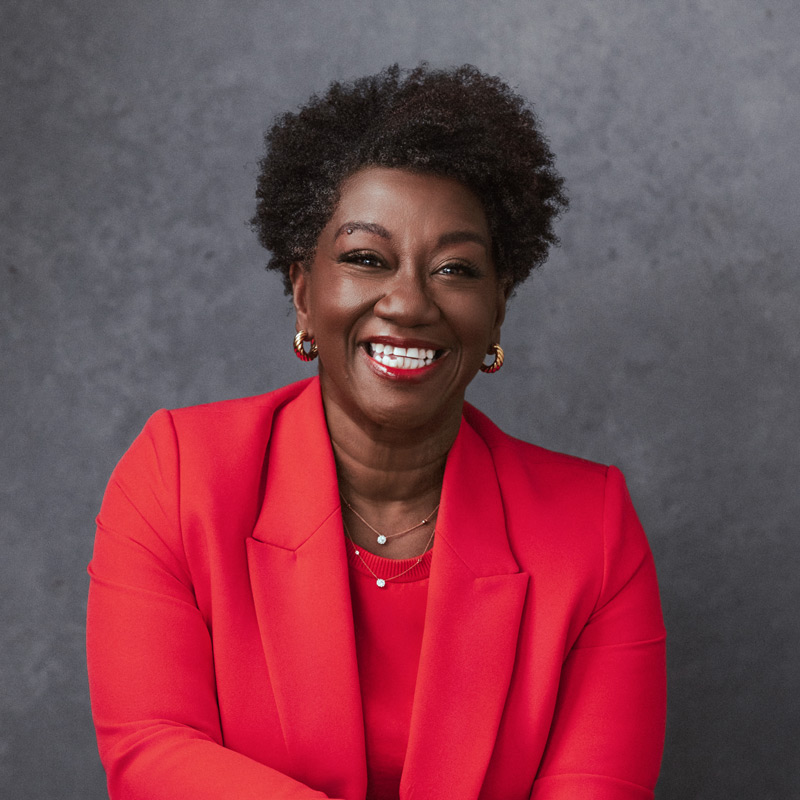 Dr. Tressie McMillian in a red suit, smiling.