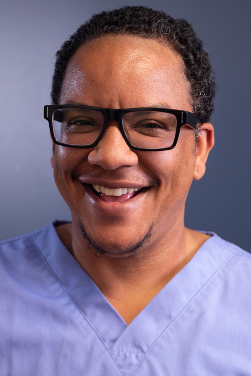 Smiling person wearing glasses in a scrubs.