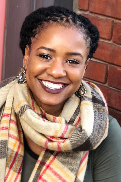 Smiling person wearing big earrings and a scarf.