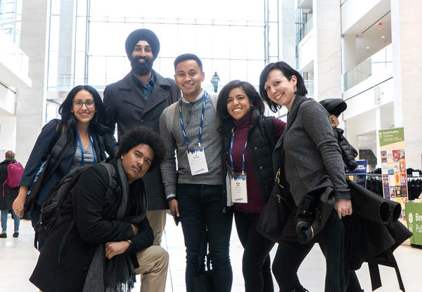 Multiracial group of people standing and kneeling in large building with Facing Race banner hanging from rafter.