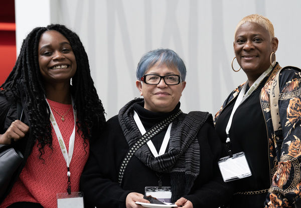 Three people smiling slightly, wearing GARE Membership Meeting badges.