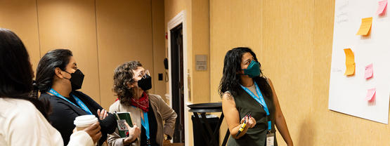 People in black respirators looking at posted notes on a board.