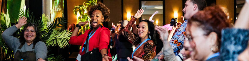 People smiling and dancing with their right hand in the air.