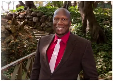 Brad Baily in brown suit, red shirt, and pink tie.